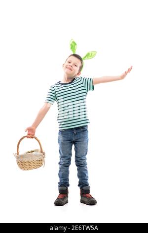 Mignon petit garçon heureux avec des oreilles de lapin tenant le panier de Pâques accueillant avec les bras ouverts. Pleine longueur isolée sur fond blanc. Banque D'Images