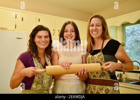 Trois femmes caucasiennes adultes attirantes à la maison boulangers tenant une goupille à roulettes dans la cuisine, Wisconsin, États-Unis Banque D'Images