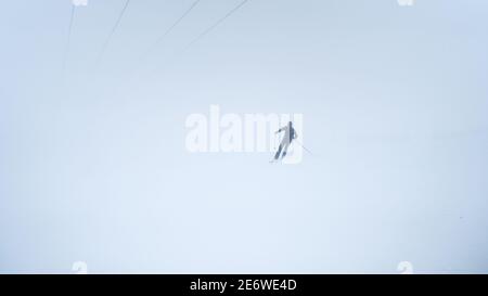 Les gens qui font du ski alpin pendant la tempête de neige. Les pistes de ski ont fermé le domaine skiable en raison du mauvais temps et du givrage. Homme athlète sur une pente enneigée par temps froid blanc Banque D'Images