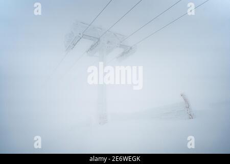 Les gens qui font du ski alpin pendant la tempête de neige. Les pistes de ski ont fermé le domaine skiable en raison du mauvais temps et du givrage. Homme athlète sur une pente enneigée par temps froid blanc Banque D'Images