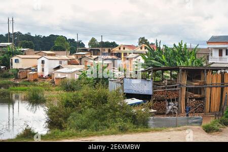 Antananarivo, Madagascar - 24 avril 2019 : maisons dans la banlieue d'Antananarivo, petit lac - rizières - à proximité, entrepôt avec matériaux de construction en bois Banque D'Images