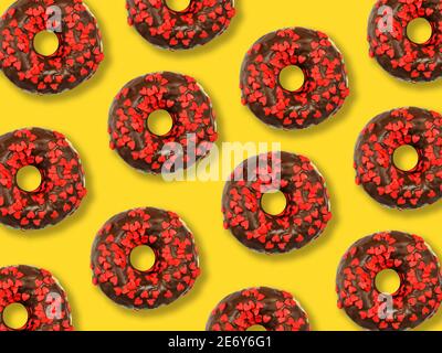 À plat, déposez les beignets dans un motif de glaçage au chocolat sur un fond jaune. Vue de dessus Banque D'Images
