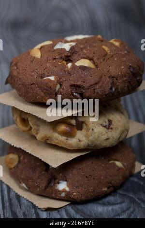 Biscuits aux flocons d'avoine avec arachides et chocolat. Plié dans une colonne et disposé avec du papier. Sur les planches de pin. Banque D'Images