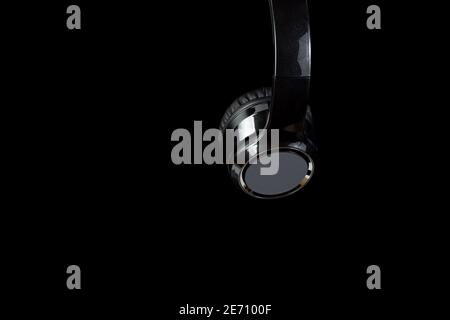 Micro-casque sans fil noir de gros plan. Sur fond noir, avec espace de copie. Banque D'Images