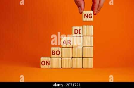 Symbole du processus d'intégration réussi. Cubes en bois empilés comme escalier sur fond orange, espace de copie. Main d'homme d'affaires. Mot « Onboarding ». Entreprise Banque D'Images