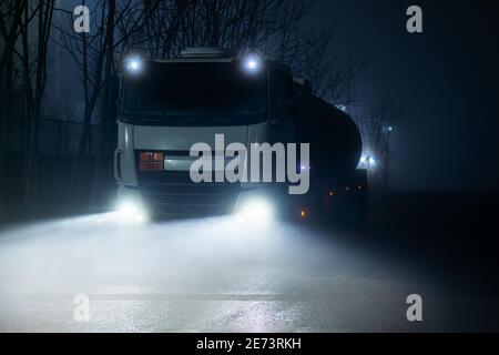 Camion-citerne avec des marchandises dangereuses circulant la nuit par jour brumeux. Banque D'Images