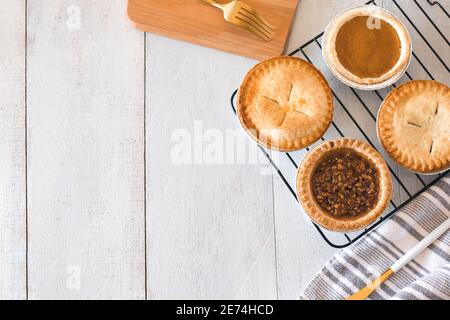 Quatre mini-chaussons directement du four sur une table en bois blanc avec un pot à lait, planche à découper Banque D'Images