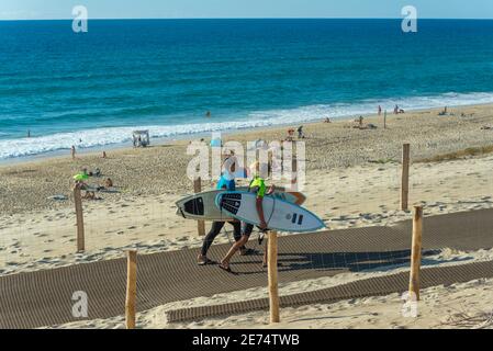 Deux jeunes gens avec surf quittent la plage de Biscarrosse. Biscarrosse Plage est une destination de surf importante sur l'océan Atlantique en France Banque D'Images