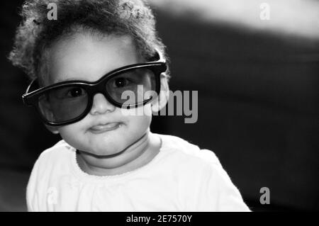 portrait noir et blanc franc de bébé portant trop de taille lunettes Banque D'Images