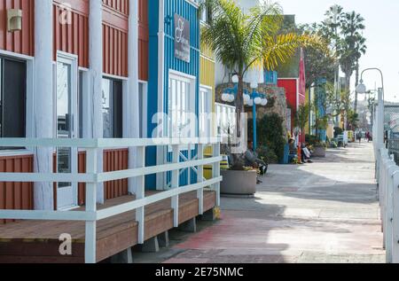 Personnes assises sur des bancs le long de la promenade du front de mer à Fisherman's Village à Marina Del Rey, Californie États-Unis, par une journée ensoleillée Banque D'Images