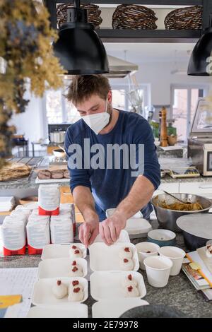 Nuremberg, Allemagne. 22 janvier 2021. Manuel Kohler, chef de l'école culinaire mobile, prépare les plats commandés dans la cuisine pour les plats à emporter. De nombreux restaurants proposent des menus de haute qualité pour être ramassent pendant le confinement. C'est également le cas au Mobile Kochkunst de Nuremberg, qui propose un forfait week-end chaque vendredi avec salade, soupe, plat principal avec viande et accompagnement, et un dessert. (À dpa 'manger à l'écluse - entre plaisir de cuisine et frustration') Credit: Daniel Karmann/dpa/Alamy Live News Banque D'Images