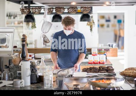 Nuremberg, Allemagne. 22 janvier 2021. Manuel Kohler, chef de l'école culinaire mobile, prépare les plats commandés dans la cuisine pour les plats à emporter. De nombreux restaurants proposent des menus de haute qualité pour être ramassent pendant le confinement. C'est également le cas au Mobile Kochkunst de Nuremberg, qui propose un forfait week-end chaque vendredi avec salade, soupe, plat principal avec viande et accompagnement, et un dessert. (À dpa 'manger à l'écluse - entre plaisir de cuisine et frustration') Credit: Daniel Karmann/dpa/Alamy Live News Banque D'Images