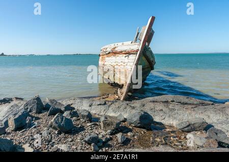 Hulk de vieux bateau de pêche en bois détroqué sur la rive de Ocean Beach Road Southland Nouvelle-Zélande. Banque D'Images