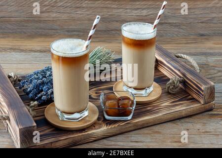 Latte ou Cappuccino avec mousse de lait et lavande dans un grand verre sur plateau en bois Banque D'Images