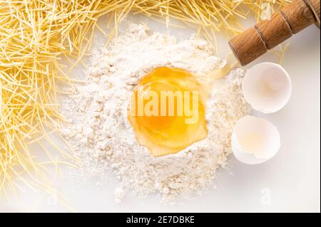œuf cassé dans la farine et les pâtes, ingrédients pour faire des nouilles Banque D'Images