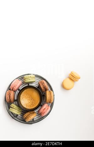 Vue en hauteur d'un plateau métallique entouré d'un café mousseux au centre, entouré de macarons colorés et savoureux en position verticale. Deux mac orange Banque D'Images