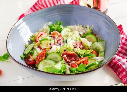 Salade cétogène avec prosciutto, tomates, concombre, laitue, oignon rouge et fromage dans un bol. Concept hors-d'œuvre sain. Keto, paleo nourriture. Banque D'Images