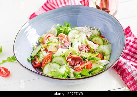 Salade cétogène avec prosciutto, tomates, concombre, laitue, oignon rouge et fromage dans un bol. Concept hors-d'œuvre sain. Keto, paleo nourriture. Banque D'Images