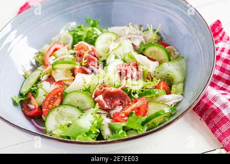 Salade cétogène avec prosciutto, tomates, concombre, laitue, oignon rouge et fromage dans un bol. Concept hors-d'œuvre sain. Keto, paleo nourriture. Banque D'Images