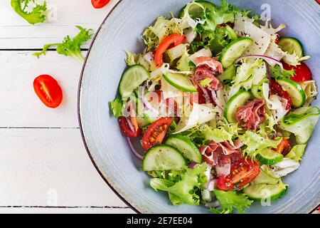 Salade cétogène avec prosciutto, tomates, concombre, laitue, oignon rouge et fromage dans un bol. Concept hors-d'œuvre sain. Keto, paleo nourriture. Vue de dessus, Banque D'Images