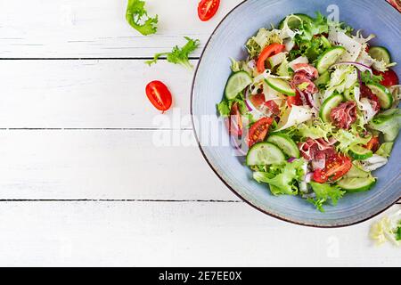 Salade cétogène avec prosciutto, tomates, concombre, laitue, oignon rouge et fromage dans un bol. Concept hors-d'œuvre sain. Keto, paleo nourriture. Vue de dessus, Banque D'Images