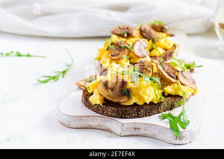 Œufs brouillés et champignons frits sur le pain. Petit-déjeuner ou brunch fait maison - œufs brouillés et sandwichs aux champignons. Banque D'Images