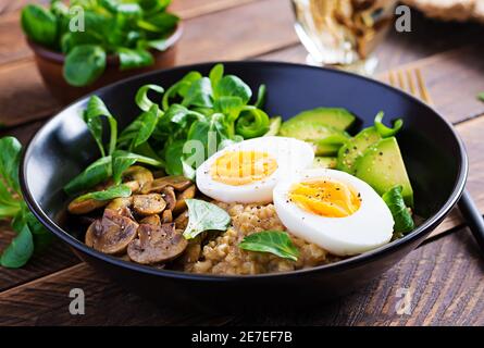 Petit déjeuner porridge de flocons d'avoine avec œufs durs, avocat et champignons frits. Une alimentation saine et équilibrée. Banque D'Images