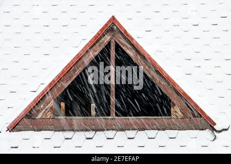 Le dormeur sans verre dans les fenêtres sur le toit enneigé. Chute de neige sur le toit de la maison avec une fenêtre sans verre. Banque D'Images