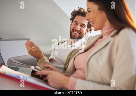 Un couple d'affaires joyeux s'amuser sur le canapé dans une atmosphère détendue dans un appartement. Affaires, couple, loisirs, ensemble Banque D'Images