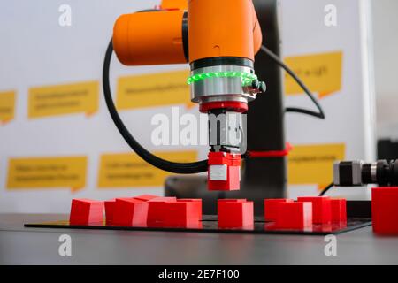 Sélectionner et placer les blocs de jouets rouges mobiles du manipulateur de bras robotisé à l'exposition robot Banque D'Images