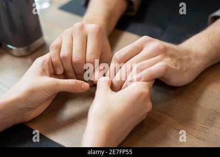 Des mains de jeunes amoreux et affectueux dates assis par servi table pour un dîner romantique dans un restaurant ou un café contemporain Banque D'Images