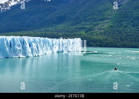 Glace bleue du glacier Perito Moreno dans le parc national des Glaciers de Patagonie, Argentine avec un bateau touristique sur l'eau turquoise du Lago Argentino dans le Th Banque D'Images