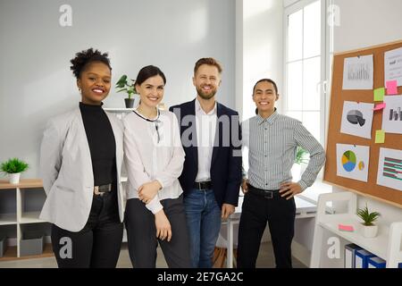 Équipe de professionnels multiraciaux heureux debout au bureau de leur entreprise de démarrage Banque D'Images