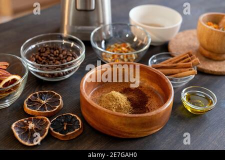 Ensemble de bols avec grains de café, fleurs sèches et tranches d'orange, bâtonnets de cannelle, fruits confits moulus et autres ingrédients pour faire du savon Banque D'Images