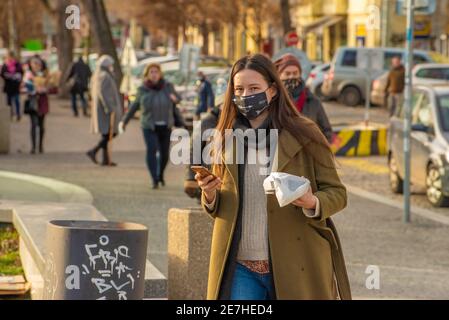 Prague, République tchèque. 01-29-2021. Portrait d'une jeune femme élégante et élégante avec un téléphone portable marchant dans le centre de Prague pendant un temps ensoleillé et froid Banque D'Images