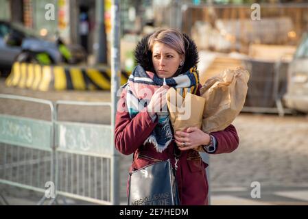 Prague, République tchèque. 01-29-2021. Portrait d'une jeune belle femme élégante fumant portant des sacs à provisions dans le centre de Prague pendant un an ensoleillé Banque D'Images