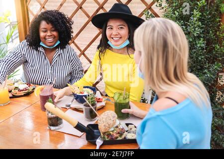 Jeunes multiraciaux prenant le petit déjeuner dans un restaurant à l'extérieur pendant le coronavirus Épidémie - Focus sur la fille asiatique Banque D'Images