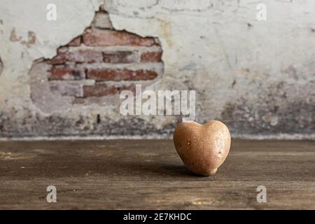 Cœur de la pomme de terre rouge sur fond de millésime. Le concept de l'agriculture, de la récolte, du végétarisme. Saint-Valentin. Carré, nourriture moche Banque D'Images