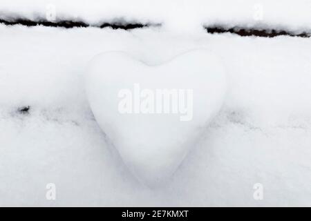 Un coeur blanc neige fait de neige sur un banc. Le concept de la Saint-Valentin. Banque D'Images