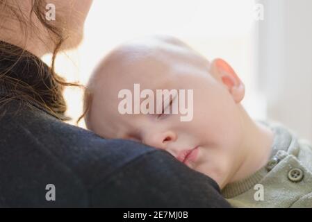 Petit garçon endormi sur l'épaule de la mère