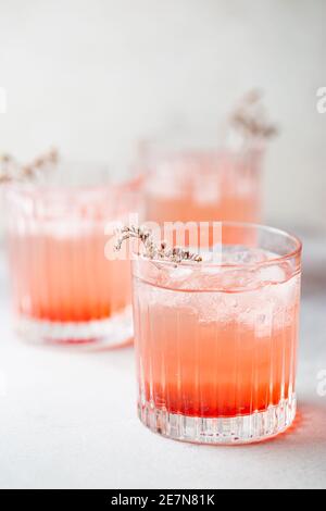 Boisson fraîche et rose à la limonade avec glace dans un verre sur fond blanc, mise au point sélective Banque D'Images