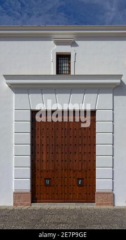 Une grande porte latérale en bois renforcé d'une église dans la ville espagnole d'Antequerra, avec une simple fenestration en pierre et un linteau, et une fenêtre au-dessus. Banque D'Images
