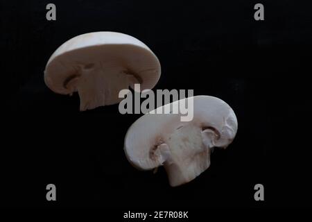 Champignons à capuchon fermé tranchés sur fond noir Banque D'Images