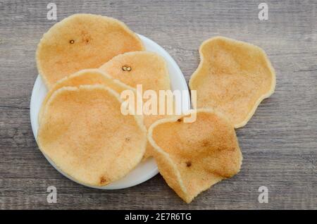 Pile de craqueur croquant de crevettes dans une assiette blanche sur une planche en bois Banque D'Images