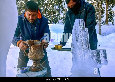 Un serveur prépare le thé près du tout premier Igloo Cafe de l'Inde, fait de neige à Gulmarg. Le café Igloo mesure environ 15 mètres et fait 26 mètres de tour et peut accueillir quatre tables et environ 16 personnes. Le café Igloo propose des tables faites de glace et de neige, avec des plats chauds servis aux visiteurs. Banque D'Images