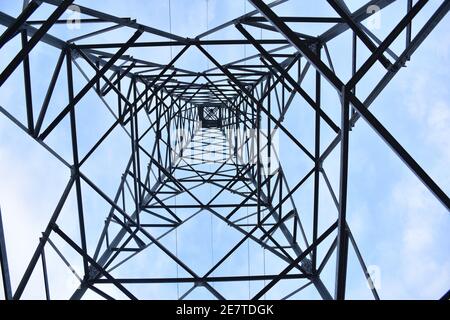 Tour d'électricité moyenne tension vue de la base. Fond bleu ciel avec nuages. Banque D'Images