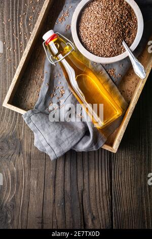 Huile de lin dans une bouteille de verre, décorée de graines entières sur fond rustique en bois avec espace de copie Banque D'Images