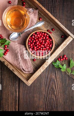 Une tasse de thé à l'aubépine chaud fait de baies fraîchement cueillies, médecine de fines herbes pour la santé du coeur sur fond rustique en bois avec espace de copie Banque D'Images