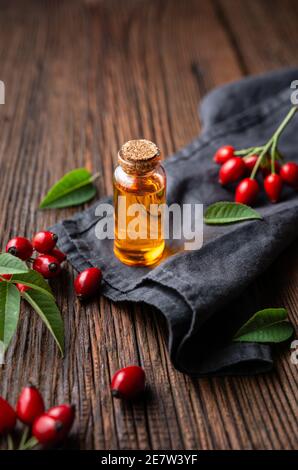 Huile de graines de rosehip pure dans une bouteille en verre, remède pour la peau et les cheveux sur fond rustique en bois Banque D'Images