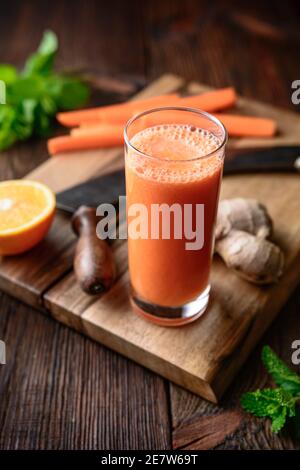 Boisson nourrissante pour le petit déjeuner, carottes fraîches, jus d'orange et de gingembre sur fond de bois rustique Banque D'Images